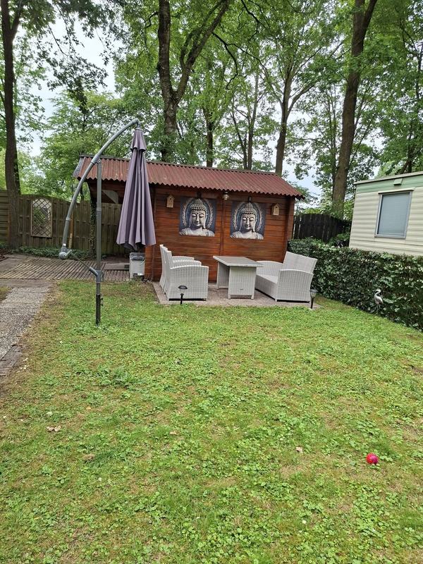 Grasveld met zitje en parasol onder de bomen