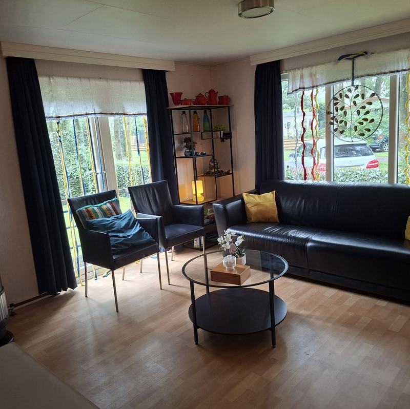 Woonkamer met zwarte bank, twee fauteuils en een ronde salontafel