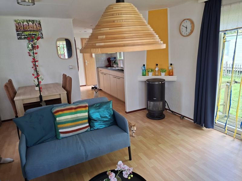 Zithoek met houten hanglamp, kachel en zicht op de keuken